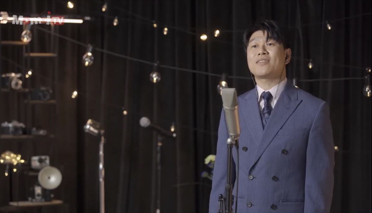 Singer at a microphone on the music set with string lights